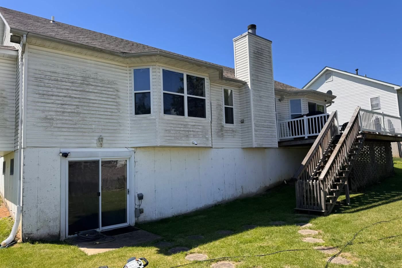 House siding covered in green algae and grime before washing