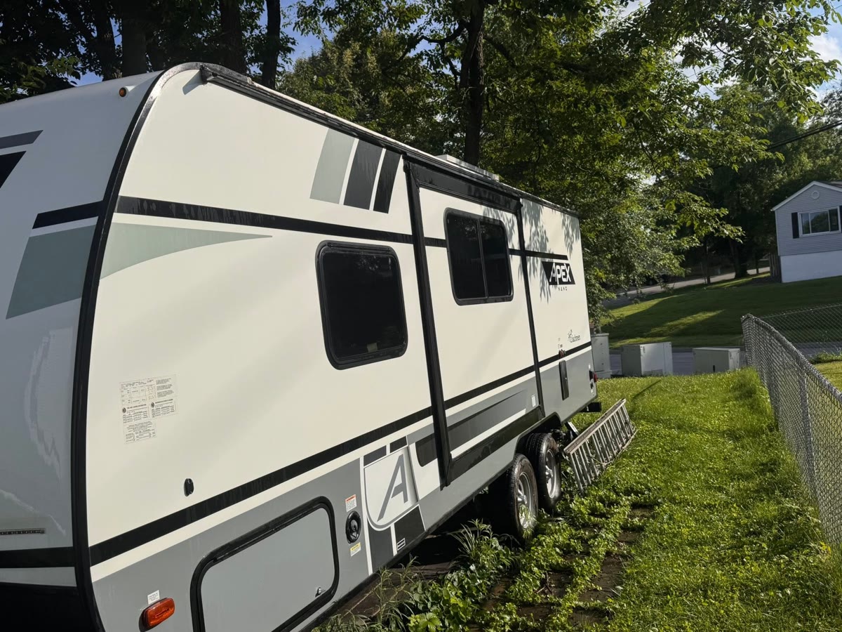A white travel trailer washed clean and parked on grass