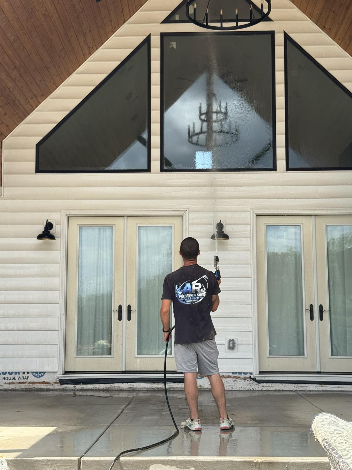 Toney washing the upper windows and siding of a two-storey home